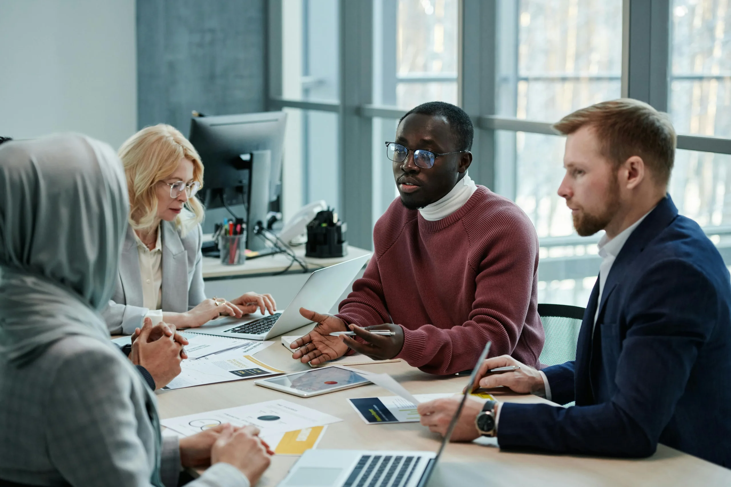 a small group of people work on their laptops in an office meetings